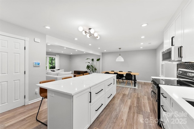 4522 Woods End Ln, Charlotte, NC 28277 - kitchen featuring black electric range oven, stainless steel microwave, light wood-style flooring, a kitchen island, and white cabinets