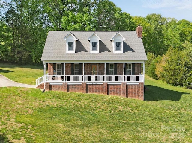 view of front facade with a porch, a front lawn, a chimney, and brick siding
