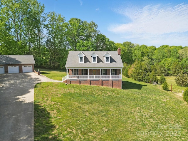 new england style home with a porch, a front lawn, a chimney, and a detached garage