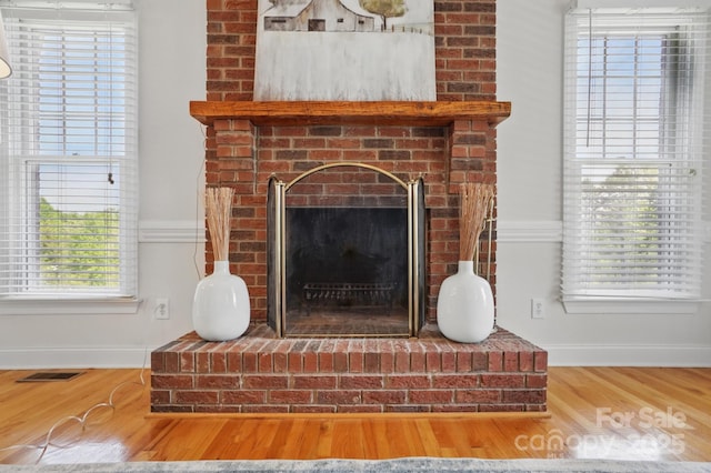interior details featuring a fireplace, wood finished floors, visible vents, and baseboards