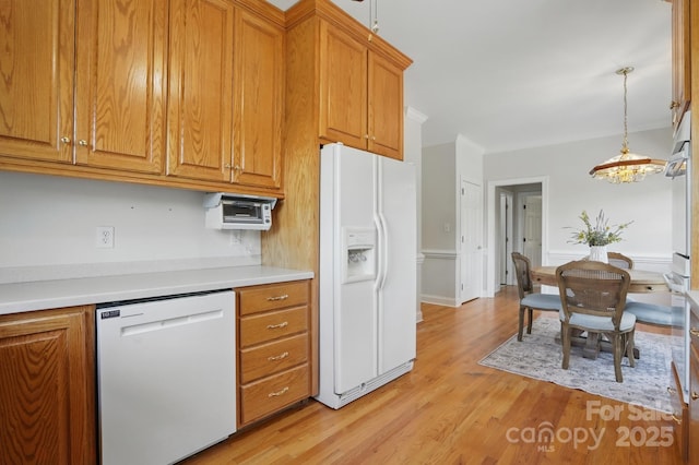 kitchen featuring light countertops, light wood-style flooring, white appliances, and brown cabinets