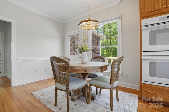 dining area with baseboards, an inviting chandelier, light wood-style floors, and crown molding