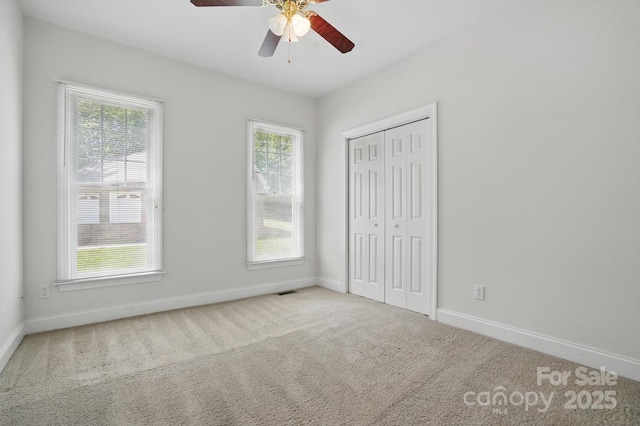 unfurnished bedroom with carpet flooring, baseboards, and multiple windows