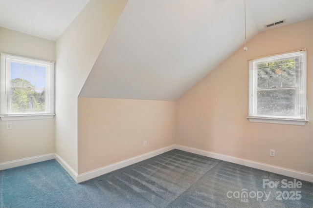 additional living space with baseboards, vaulted ceiling, visible vents, and carpet flooring