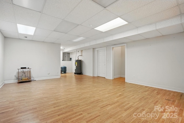 interior space with electric panel, water heater, light wood-style flooring, baseboards, and a paneled ceiling