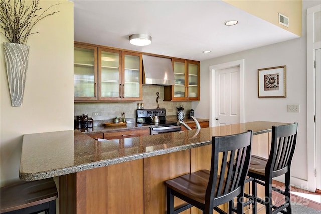 27 Stokes Dr, Asheville, NC 28805 - kitchen with stainless steel electric range, exhaust hood, brown cabinetry, a breakfast bar, and backsplash