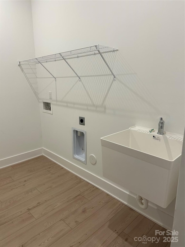 laundry room with laundry area, wood finished floors, washer hookup, a sink, and baseboards