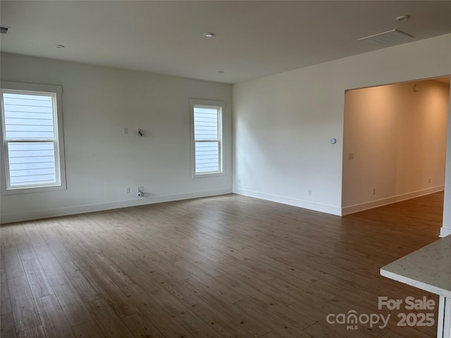 spare room featuring visible vents, baseboards, and dark wood finished floors