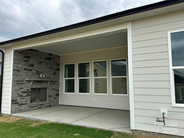 exterior space featuring a patio area, stone siding, and an outdoor stone fireplace