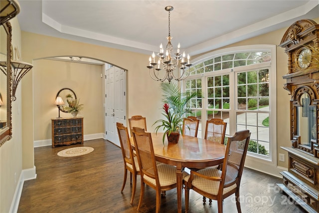 dining room with baseboards, a raised ceiling, arched walkways, dark wood-style floors, and an inviting chandelier