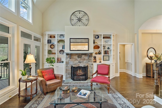 living room with arched walkways, a high ceiling, wood finished floors, and a fireplace