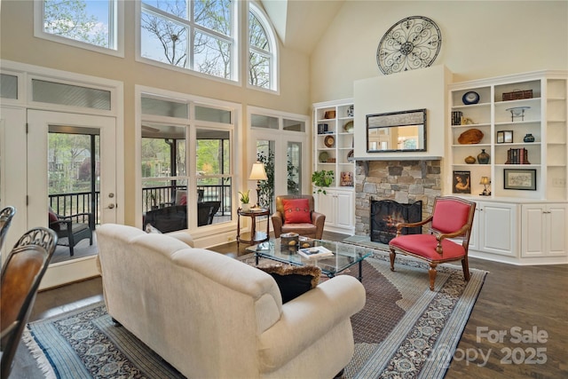 living area featuring a fireplace, high vaulted ceiling, and dark wood finished floors