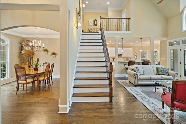stairs featuring arched walkways, baseboards, wood finished floors, and crown molding