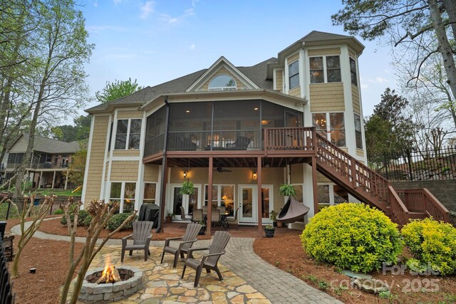 back of house featuring a sunroom, stairs, a patio, a fire pit, and a shingled roof