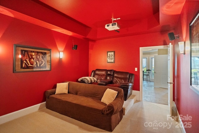 cinema room with a tray ceiling, carpet, and baseboards