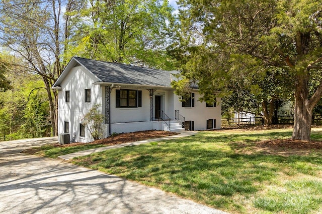 view of front facade featuring a front yard, brick siding, central AC unit, covered porch, and roof with shingles