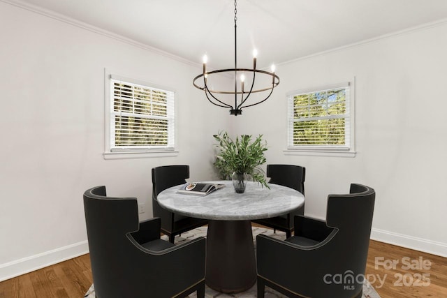 dining space featuring a chandelier, wood finished floors, baseboards, and ornamental molding
