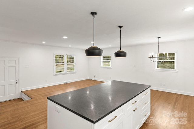 kitchen with dark countertops, wood finished floors, a center island, and recessed lighting