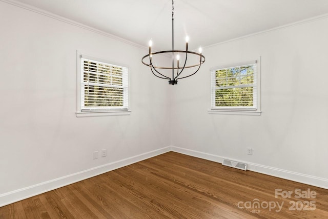 unfurnished dining area featuring a chandelier, baseboards, ornamental molding, and dark wood finished floors
