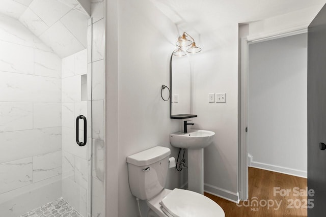 full bath featuring a stall shower, toilet, wood finished floors, baseboards, and a sink