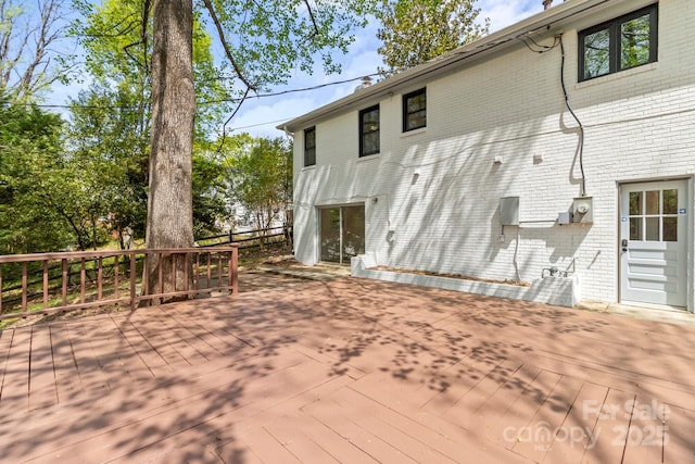 back of property featuring brick siding and a wooden deck