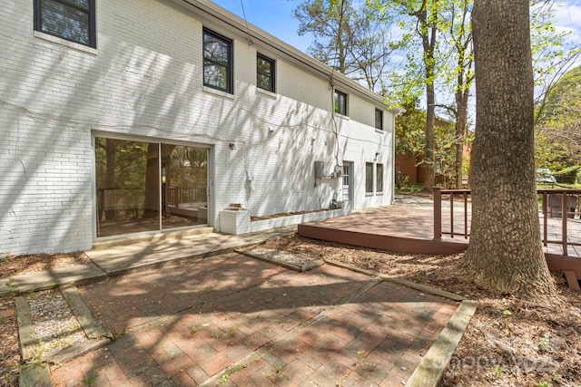 back of property with brick siding, a patio area, and a deck