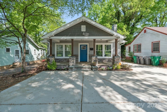 view of front of property featuring board and batten siding, stone siding, and covered porch