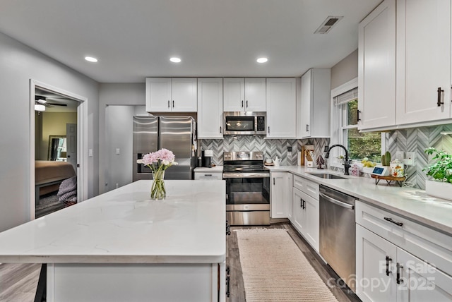 kitchen featuring white cabinetry, visible vents, a center island, appliances with stainless steel finishes, and a sink
