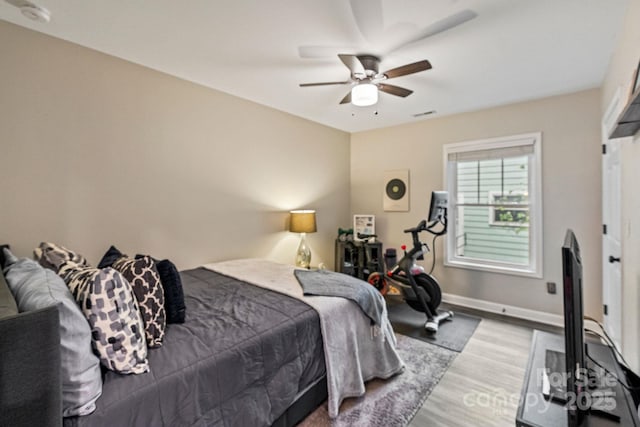 bedroom featuring wood finished floors, baseboards, a ceiling fan, and visible vents