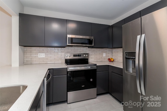kitchen with backsplash, light countertops, appliances with stainless steel finishes, and light tile patterned floors
