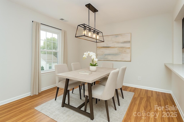 dining room with visible vents, light wood-style flooring, a chandelier, and baseboards