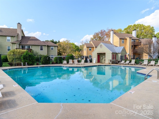 community pool featuring a patio area, fence, and a residential view