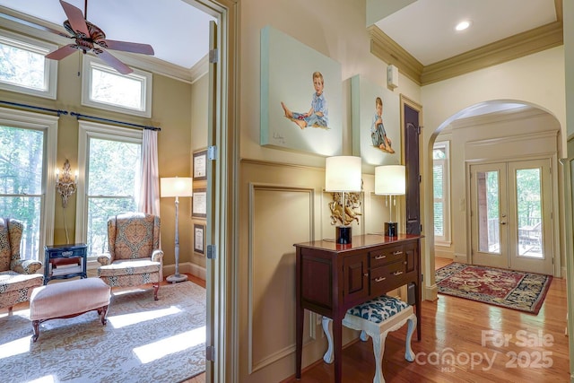 foyer entrance featuring crown molding, wood finished floors, ceiling fan, french doors, and arched walkways