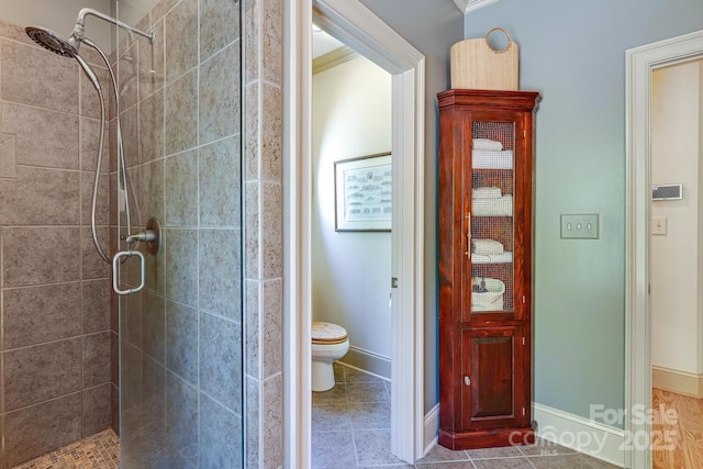 bathroom with tile patterned floors, baseboards, a shower stall, and toilet