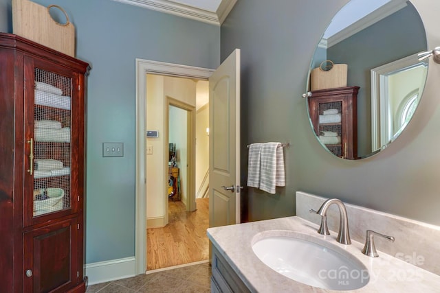 bathroom featuring baseboards, ornamental molding, tile patterned flooring, and vanity