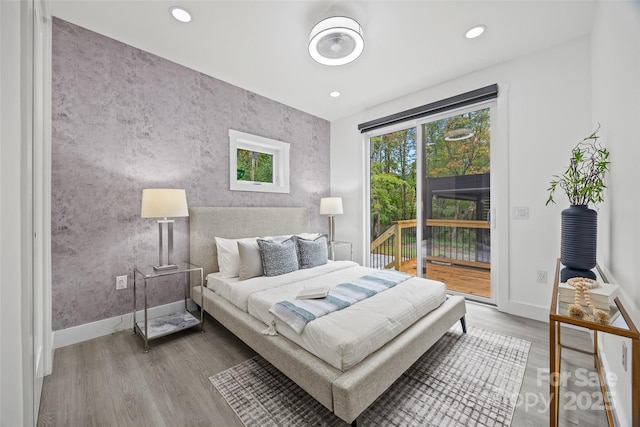 bedroom with multiple windows, wood finished floors, baseboards, and access to outside