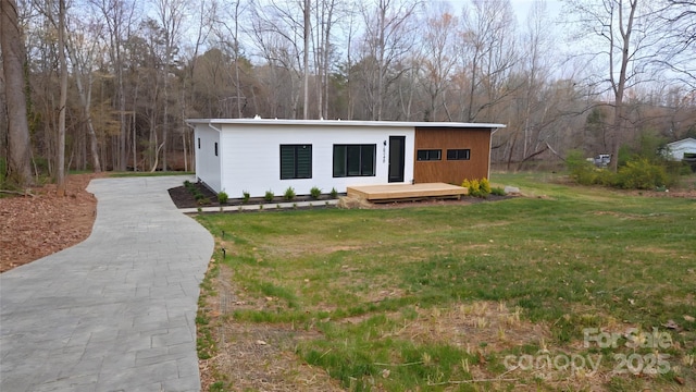 view of front of house featuring a view of trees and a front lawn