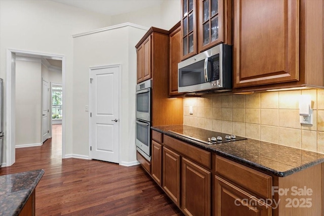 9506 Minnie Lemmond Ln Unit 170, Mint Hill, NC 28227 - kitchen with stainless steel appliances, dark wood-type flooring, glass insert cabinets, tasteful backsplash, and brown cabinets