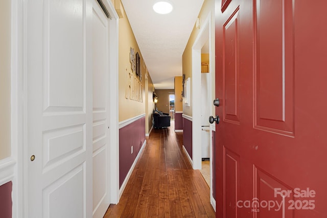 corridor with dark wood-style flooring and wainscoting