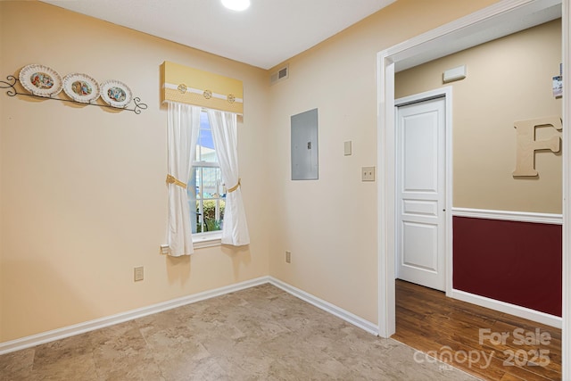 unfurnished room featuring baseboards, visible vents, and electric panel