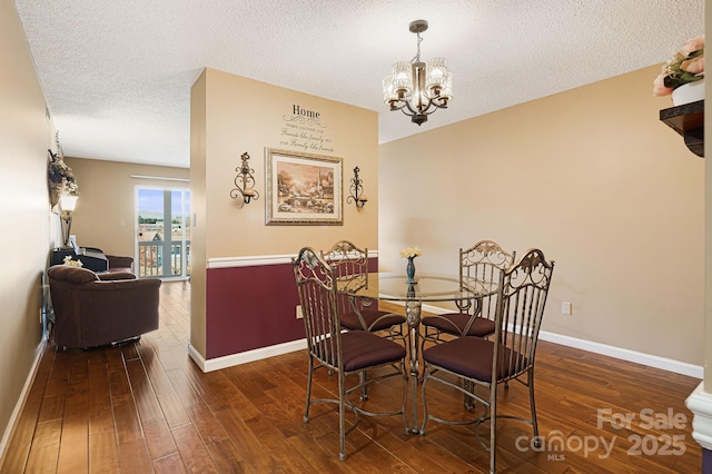 dining space with hardwood / wood-style floors, a textured ceiling, baseboards, and an inviting chandelier