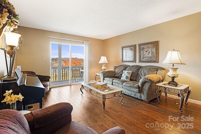 living area with a textured ceiling, baseboards, and wood finished floors