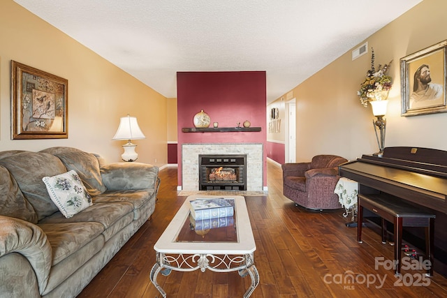 living area featuring a fireplace with flush hearth, dark wood-style floors, visible vents, and a textured ceiling