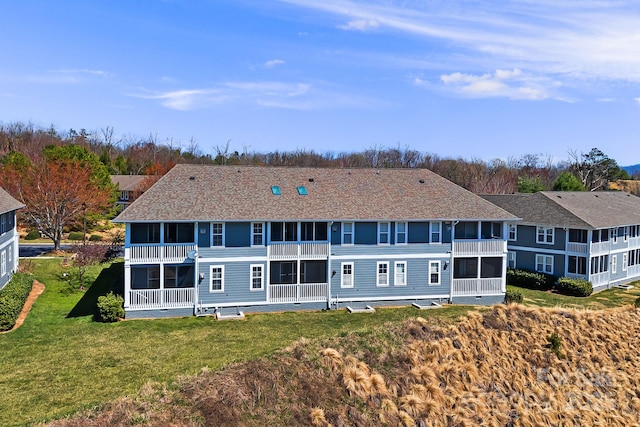 back of house featuring a balcony and a lawn