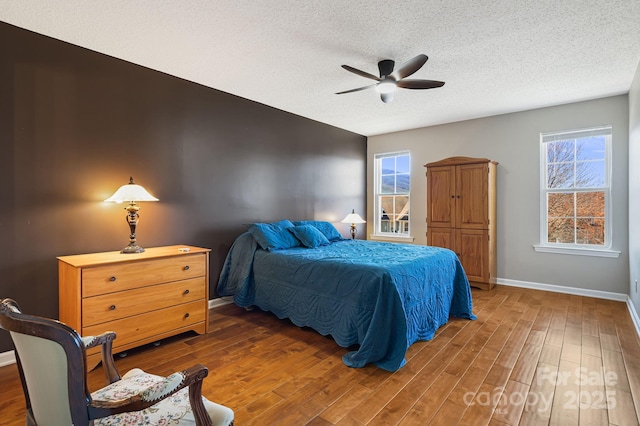 bedroom featuring baseboards, a textured ceiling, wood finished floors, and ceiling fan
