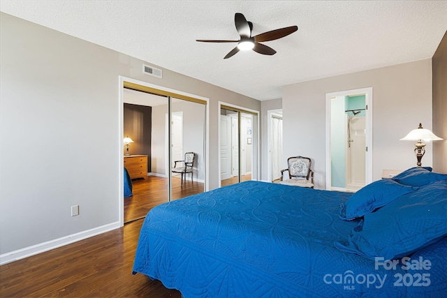 bedroom featuring a ceiling fan, wood finished floors, a textured ceiling, multiple closets, and baseboards