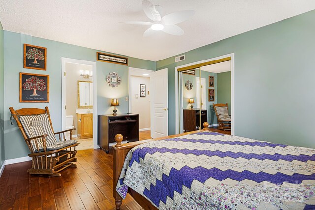 bedroom with a closet, a textured ceiling, visible vents, baseboards, and wood-type flooring