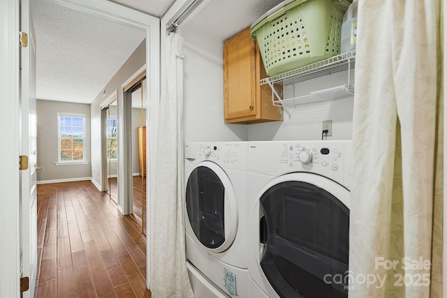 laundry room featuring wood finished floors, a textured ceiling, baseboards, independent washer and dryer, and cabinet space