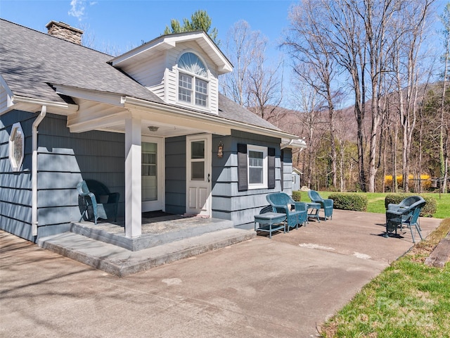 195 Nature Ln, Waynesville, NC 28786 - exterior space with a chimney, a shingled roof, a porch, and a patio area