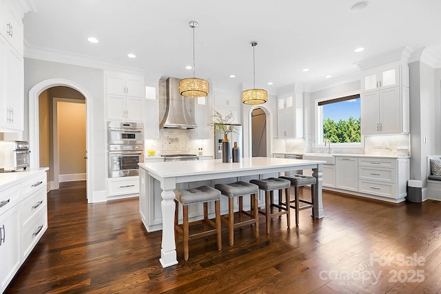 1311 Sunnys Halo Ln, Waxhaw, NC 28173 - kitchen with double oven, wall chimney exhaust hood, arched walkways, crown molding, and tasteful backsplash